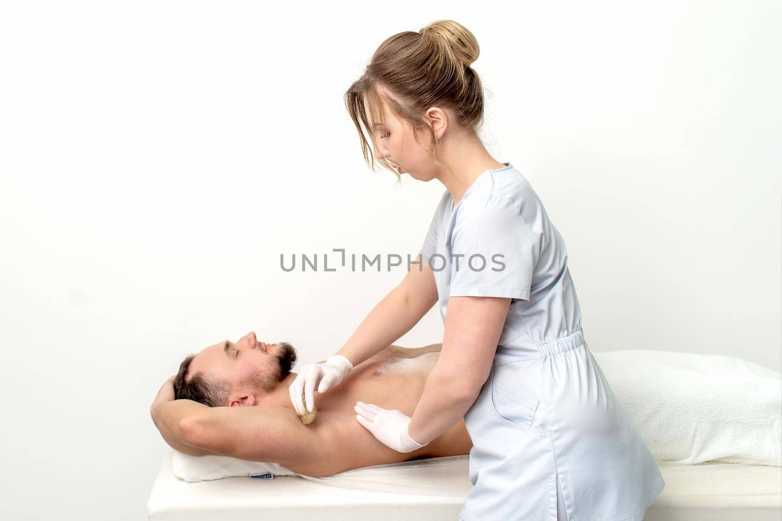 Young man receiving waxing underarm by okskukuruza