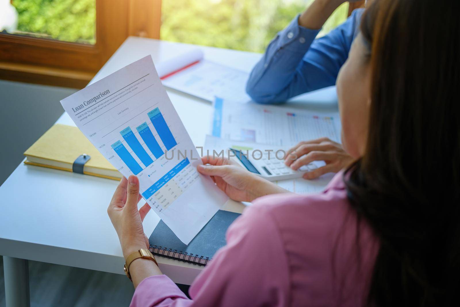 Negotiation, Analysis, Discussion, Portrait of an Asian young economist and marketer pointing to a financial data sheet to plan investments to prevent risks and losses for the company