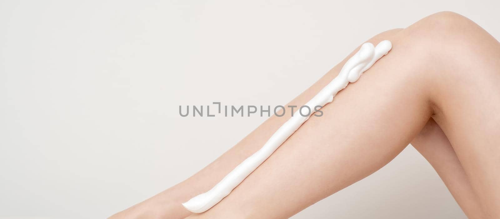 Female nice long slim bare legs with shaving foam on white background