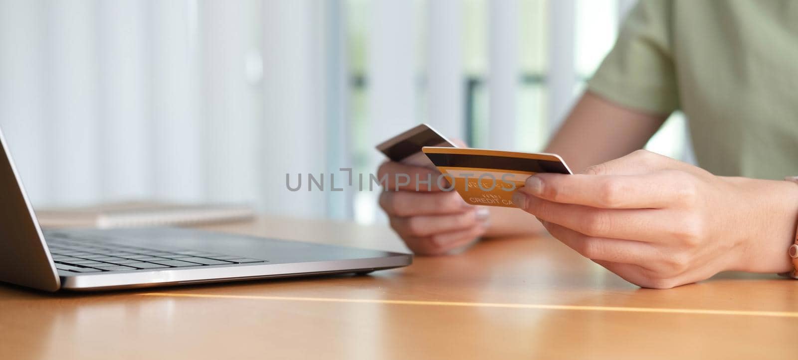 Online shopping. Young woman holding credit card and using laptop at home. African american girl working on computer at cafe. Business, e-commerce, internet banking, finance, freelance concept by wichayada