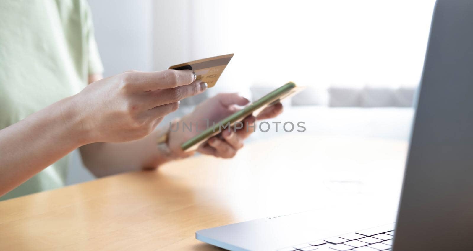 Close-up Of A Woman Holding Credit Card In Hand Doing Online Shopping Using Smart Phone by wichayada