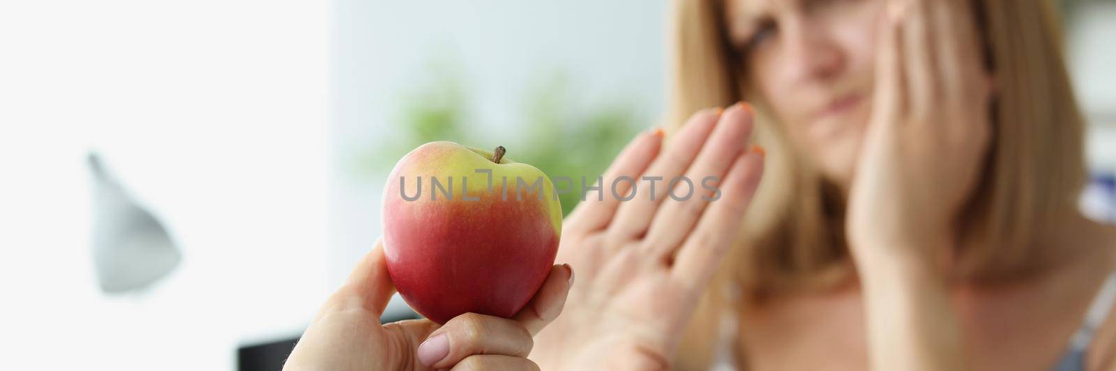 Portrait of person give apple to friend and woman refuse to eat because of tooth pain. Hold hand near face. Dental problem, healthcare, toothache concept