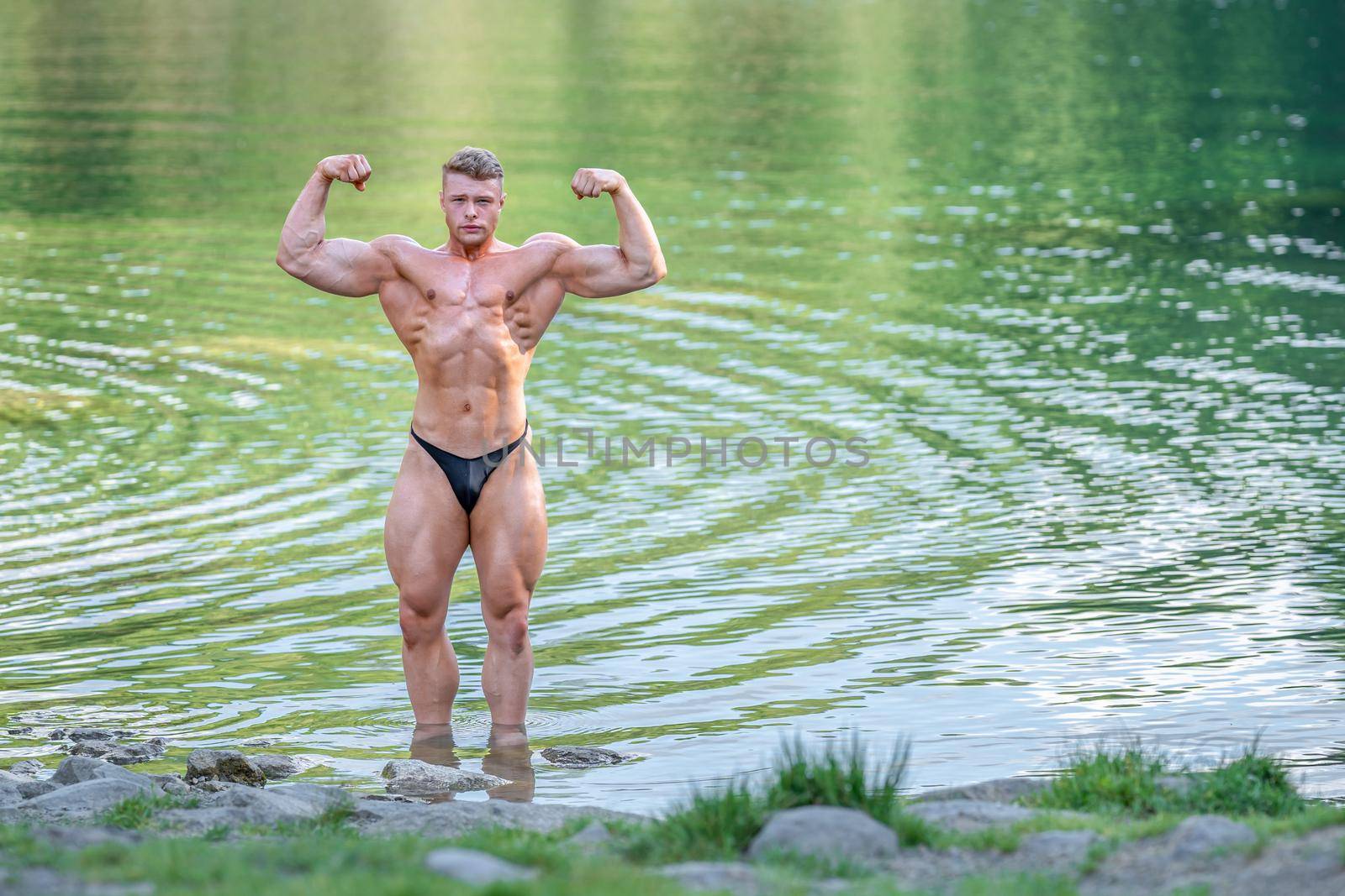 male bodybuilder in the water in nature.
