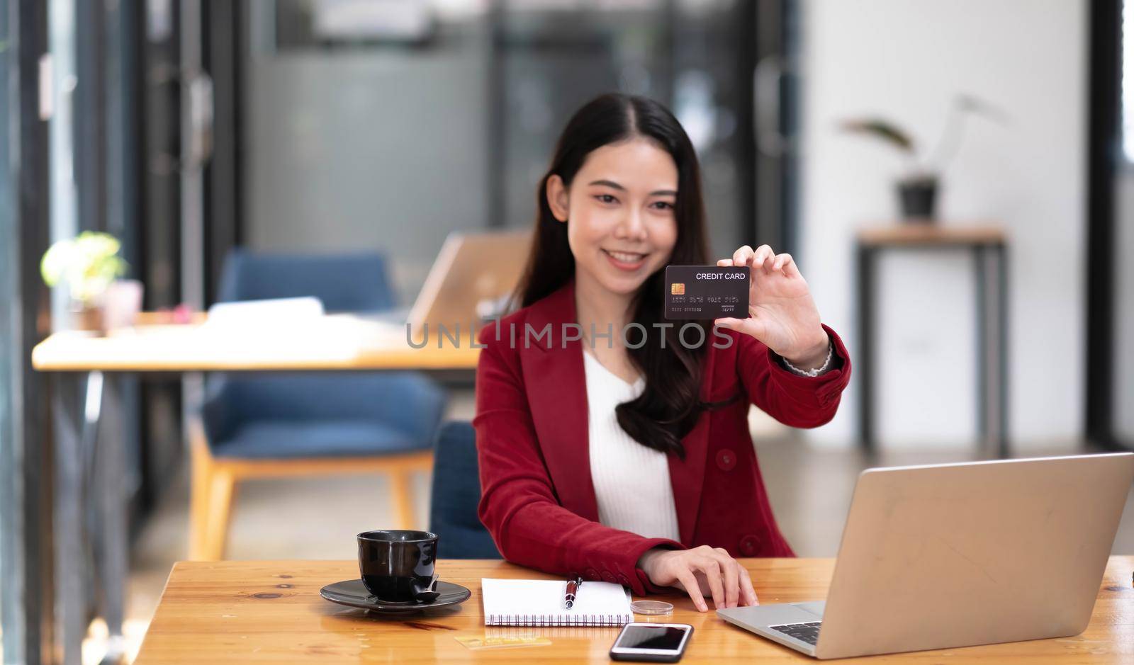 Young Asian businesswoman enjoy shopping online using credit card. Looking at camera.