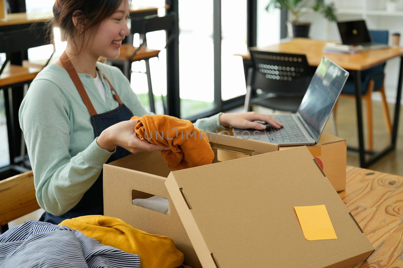 Freelance woman seller prepare parcel box of product for deliver to customer at home office. Online selling, e-commerce, packing, shipping, new normal concept.