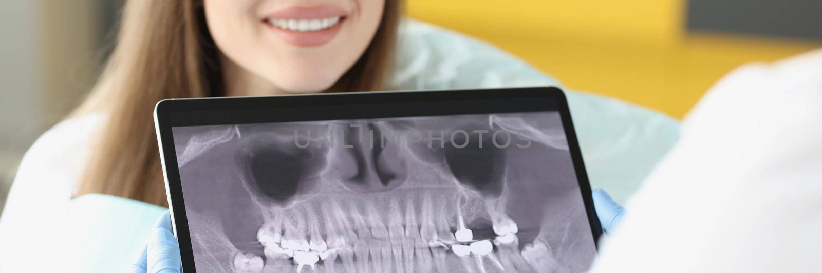 Dental consultation in clinic and doctor examine teeth x ray on digital tablet screen by kuprevich