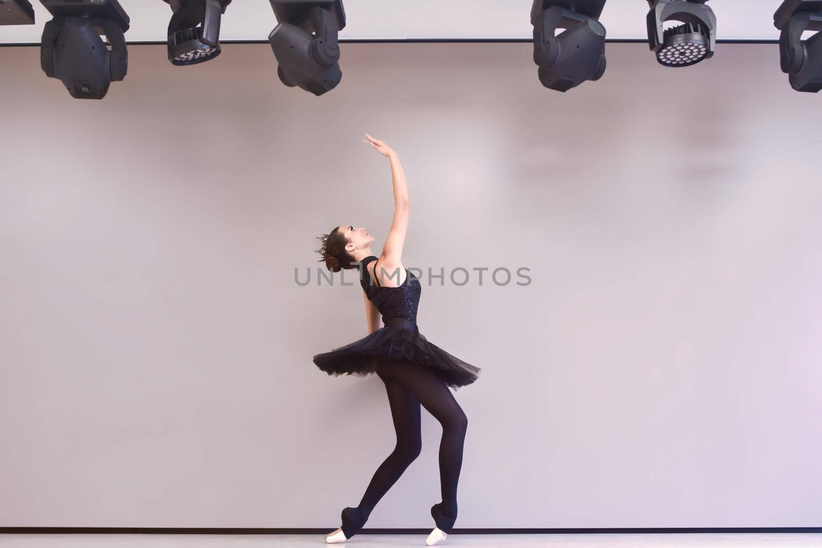 Young ballet dancer black swan practicing before performance in black tutu, classical dance studio, copy space