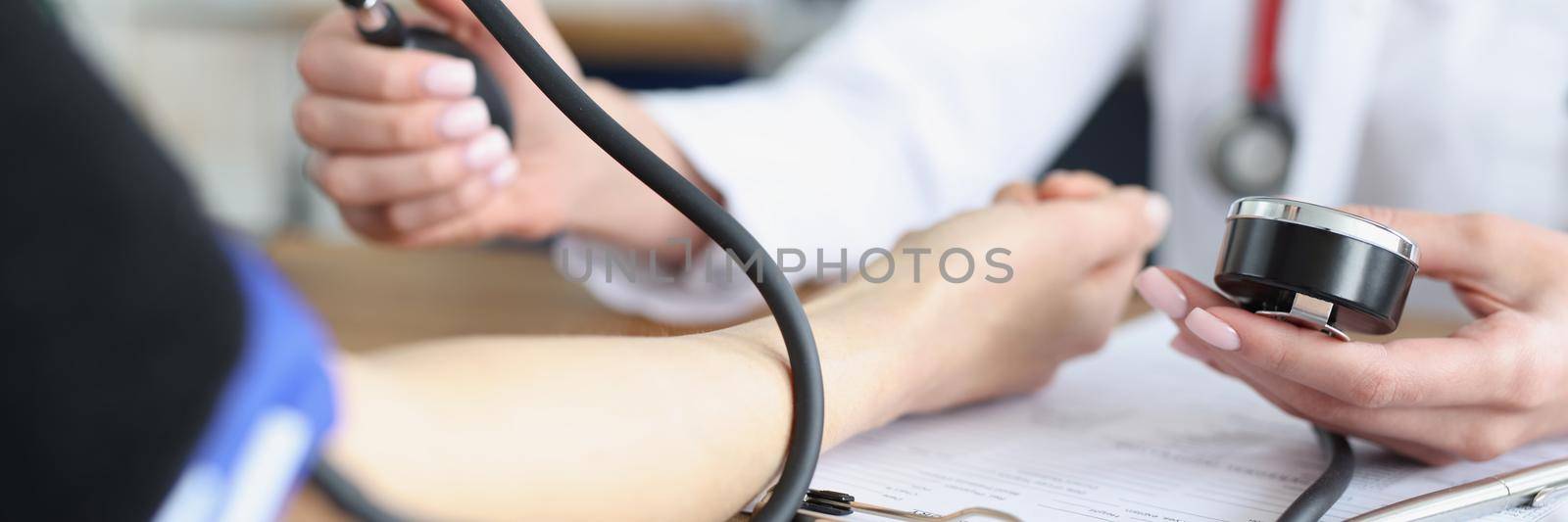 Female therapist taking blood pressure and examining patient by kuprevich