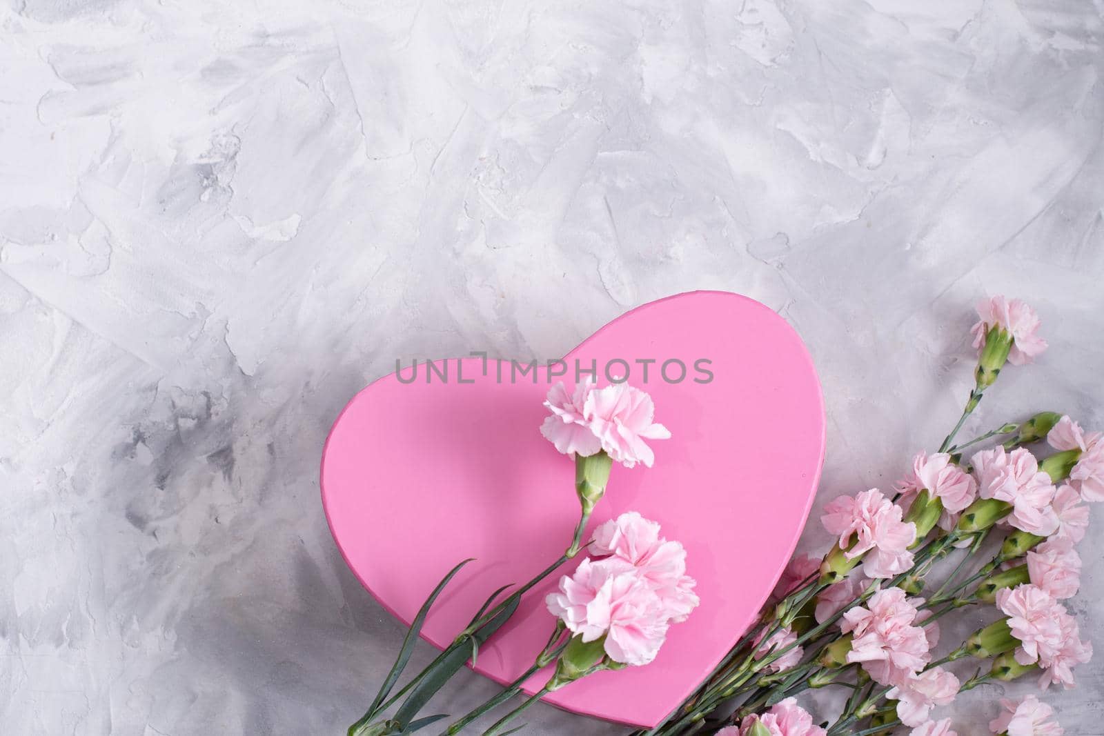 pink carnations and a heart-shaped box on a light gray cement background, a gift for mother's day, valentine's day. High quality photo