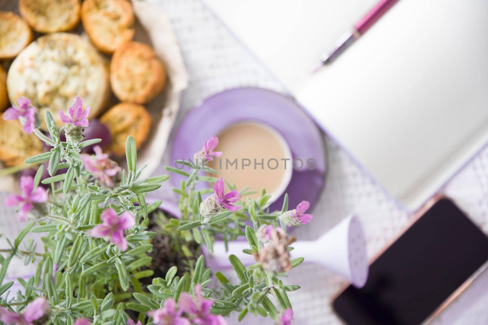 Lavender french breakfast, goat cheese and oven baked baguette, notepad, smartphone, flat lay food, female hand dipping slice of bread in cheese,depth of field, photo in blur quality photo