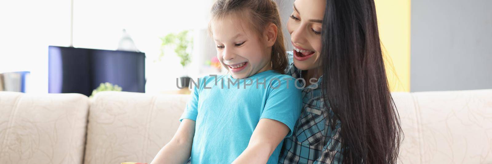 Portrait of cheerful child girl open present box and express happy emotions. Mother make surprise for daughters birthday. Family, celebration party concept