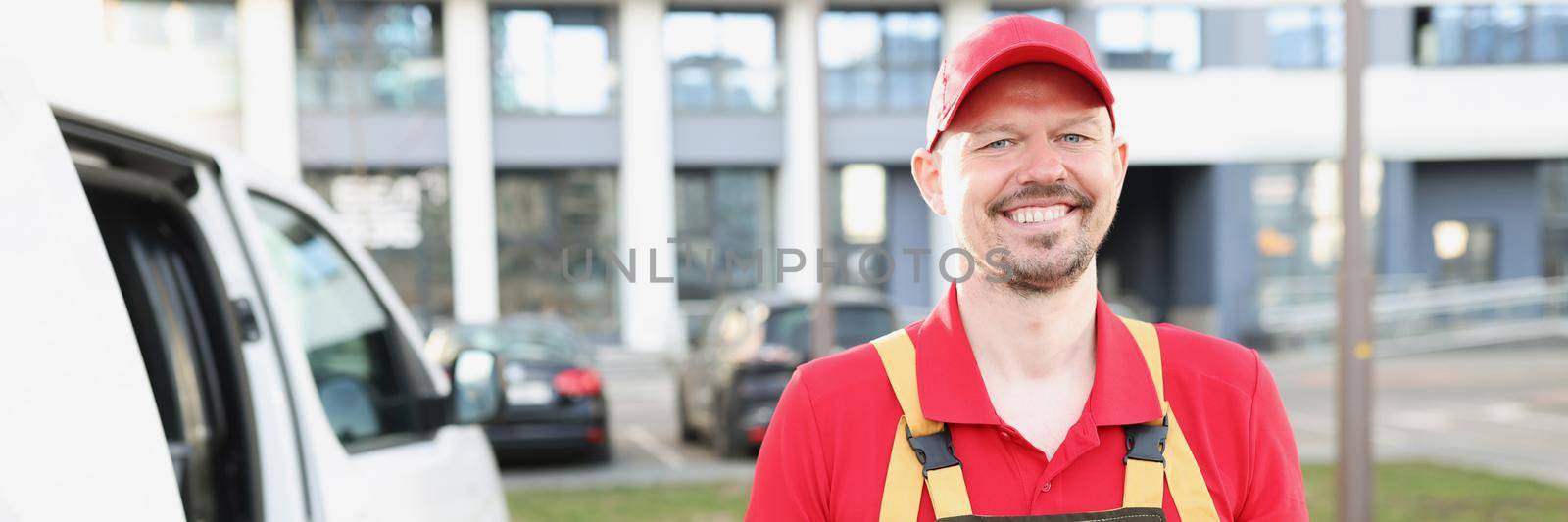 Smiling delivery man stand on street with delivery receipt paper and wait for client by kuprevich
