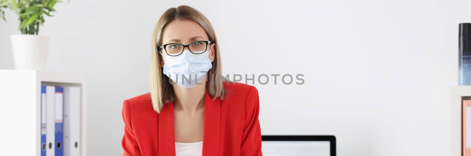 Portrait of cute manager in medical mask posing in office. Preventive measures to protect against virus. Social distancing and quarantine time idea. Coronavirus outbreak concept