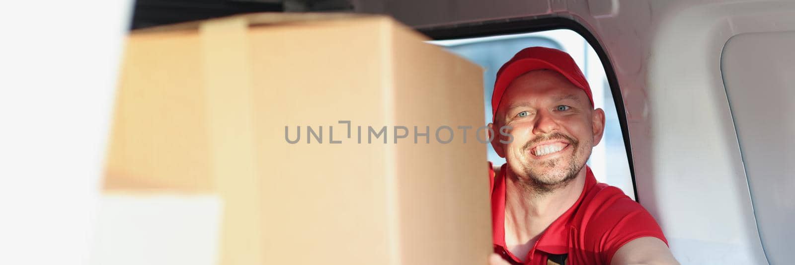 Man enjoying work putting boxes in truck for further delivery on address by kuprevich