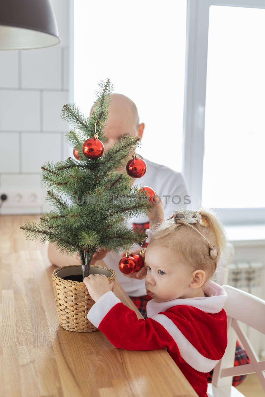 Father with toddler daughter with cochlear implants having fun in christmas living room - inclusion and innovating treatment for deafness with cochlear implant surgery by Satura86