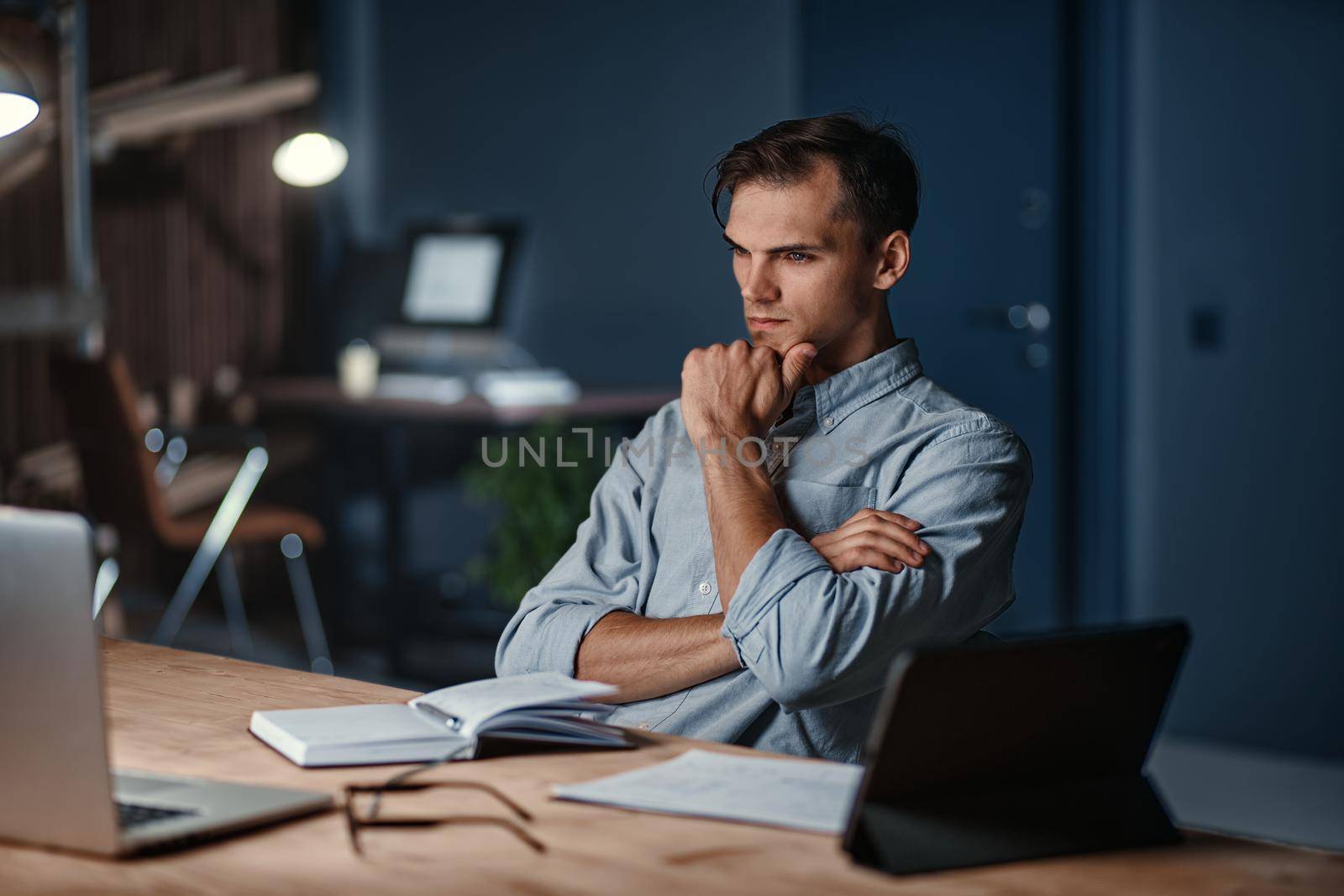 thoughtful tired businessman sitting at his desk at night in the office. close-up.