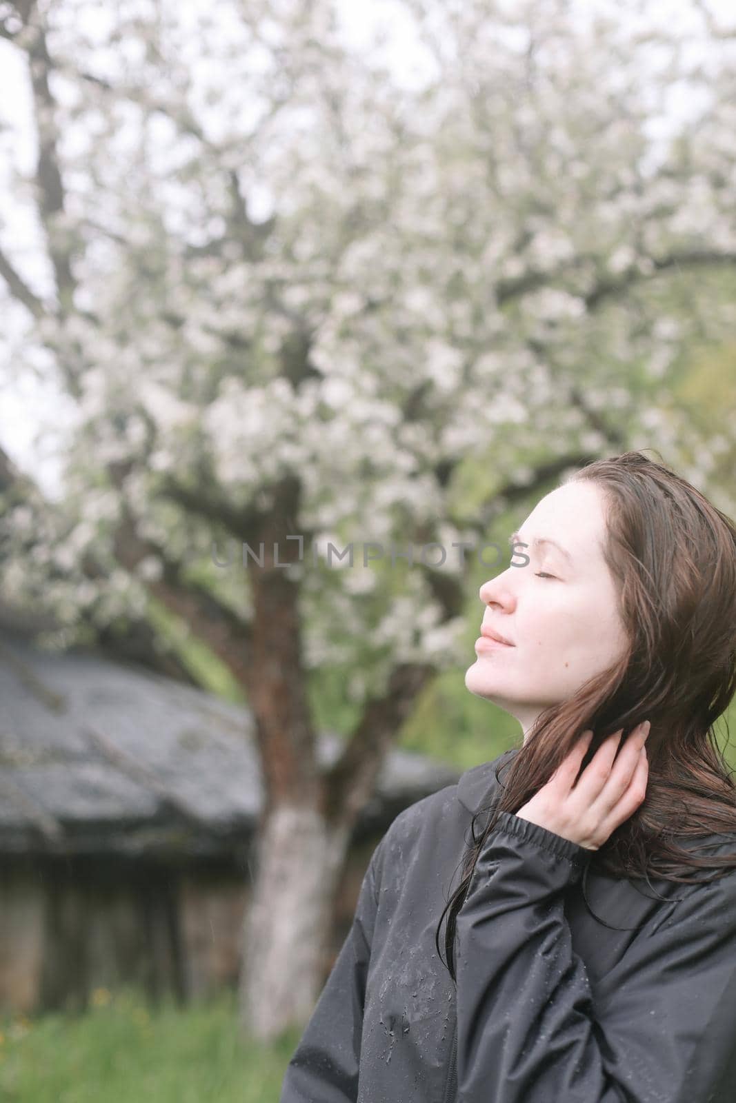 emotional portrait of a young woman standing alone under rain outdoors in spring