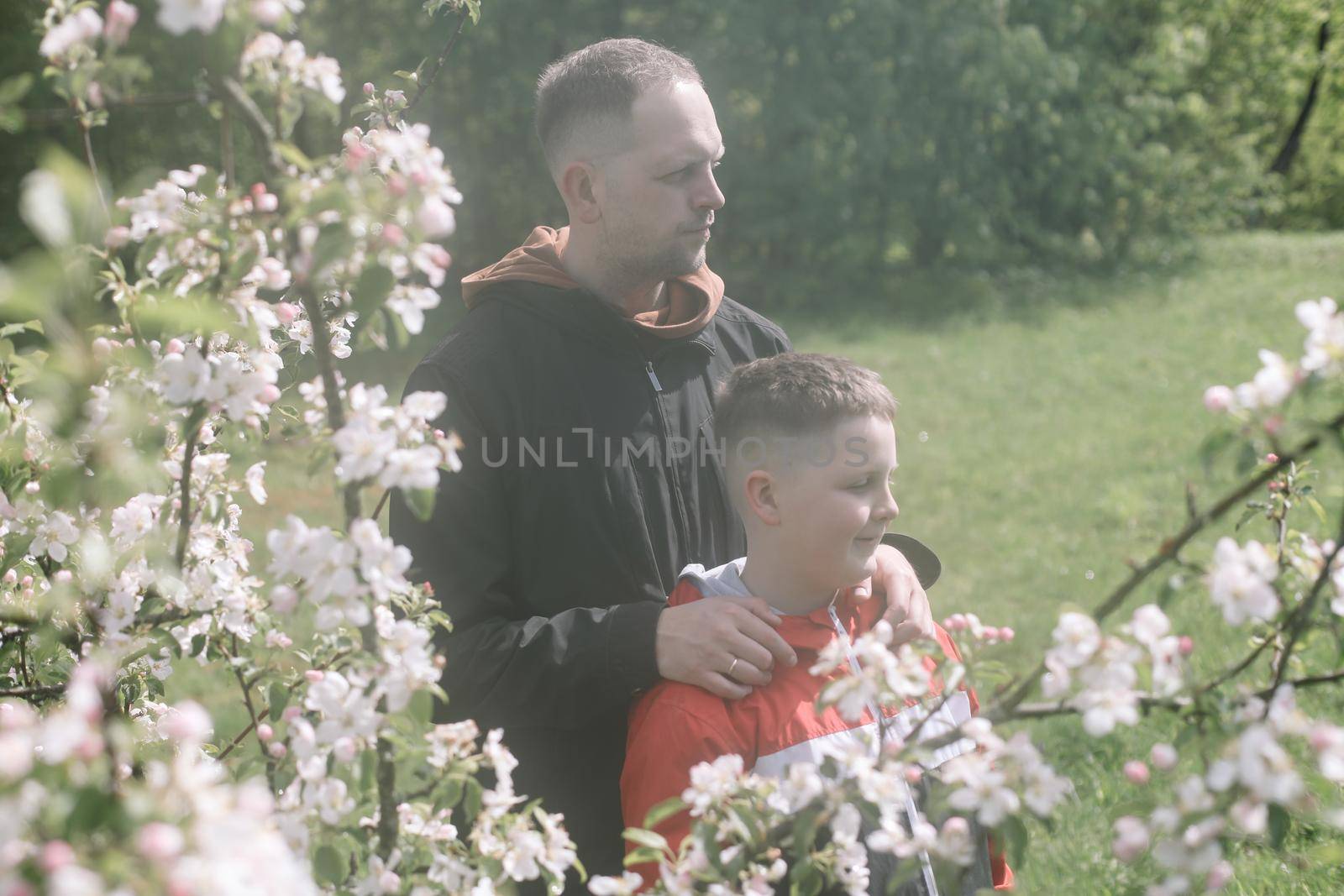 Teenager boy with father together in park in spring.