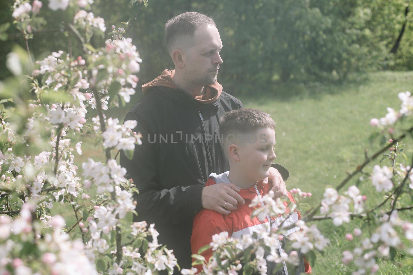 Teenager boy with father together in park in spring by paralisart