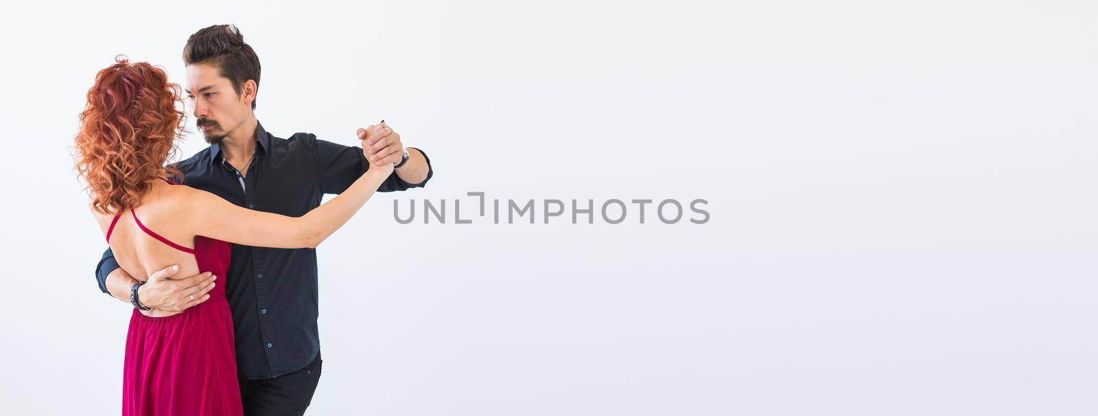 Banner social dance, bachata, kizomba, salsa, tango concept - Woman dressed in red dress and man in a black costume over white background with copyspace by Satura86