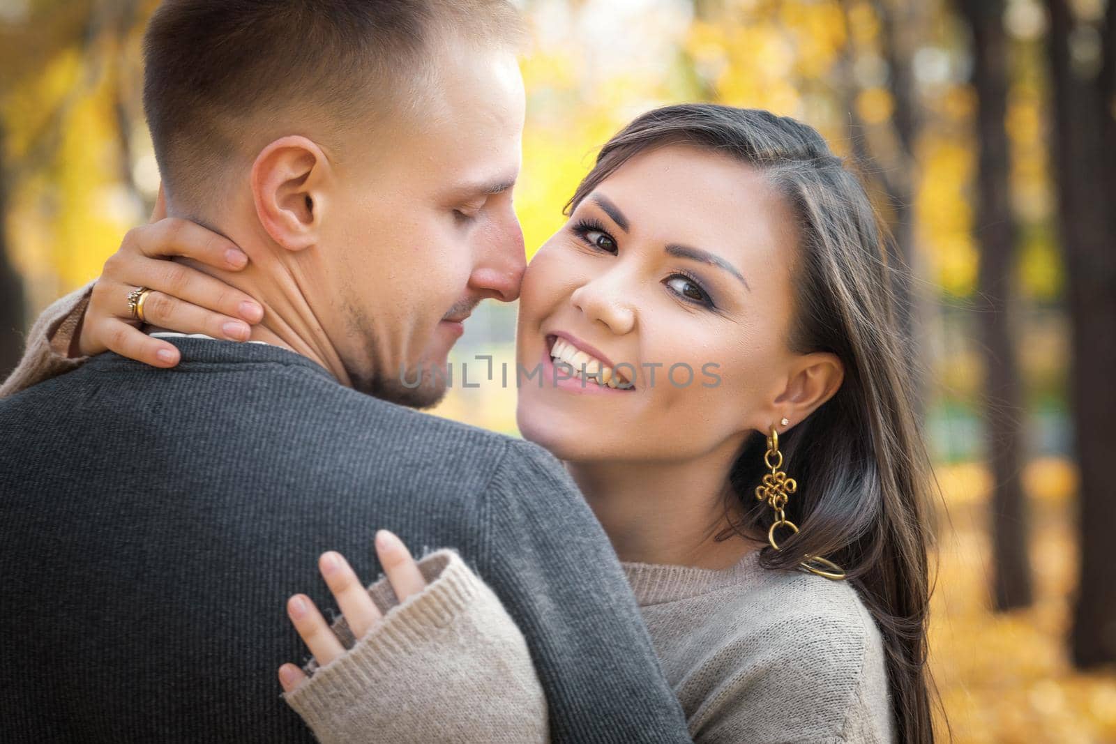 Happy smiling young woman hugging her husband on a date in a city park at the weekend.