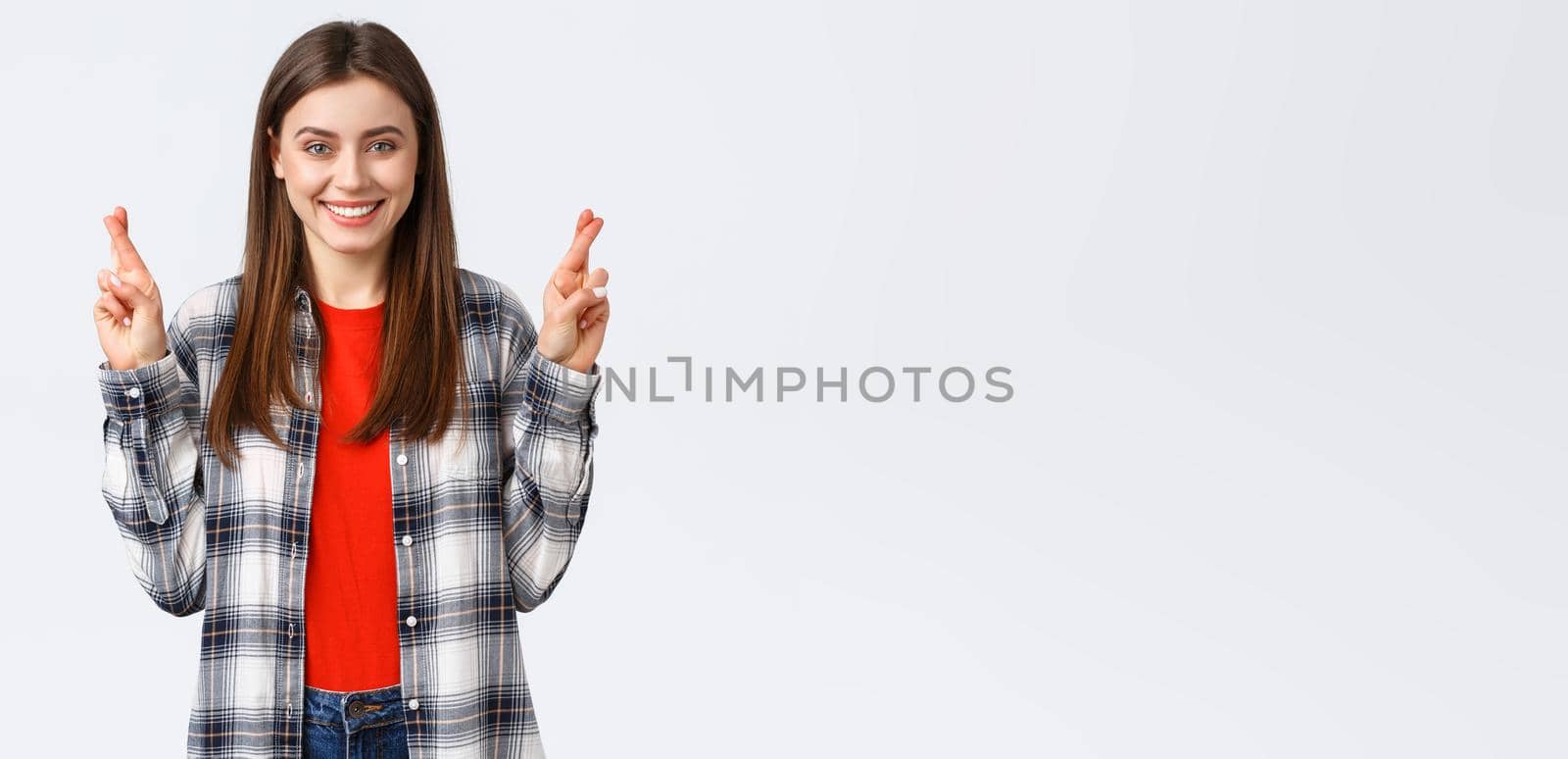 Lifestyle, different emotions, leisure activities concept. Hopeful cute caucasian girl in checked shirt, making wish, cross fingers good luck and smiling optimistic, white background.