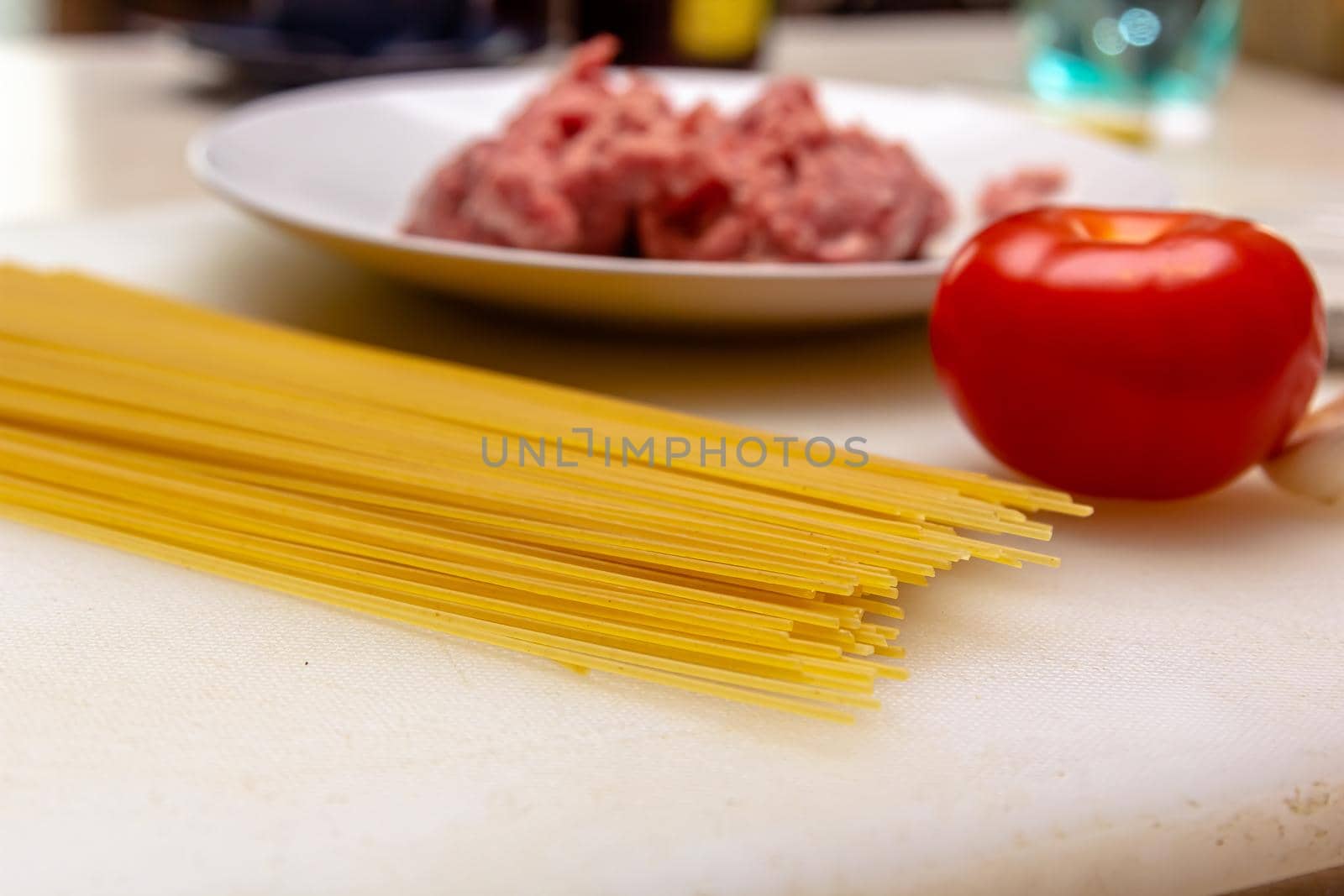 Bolognese sauce with tomato sauce and spaghetti dry on a cutting board. On a wooden background by Milanchikov