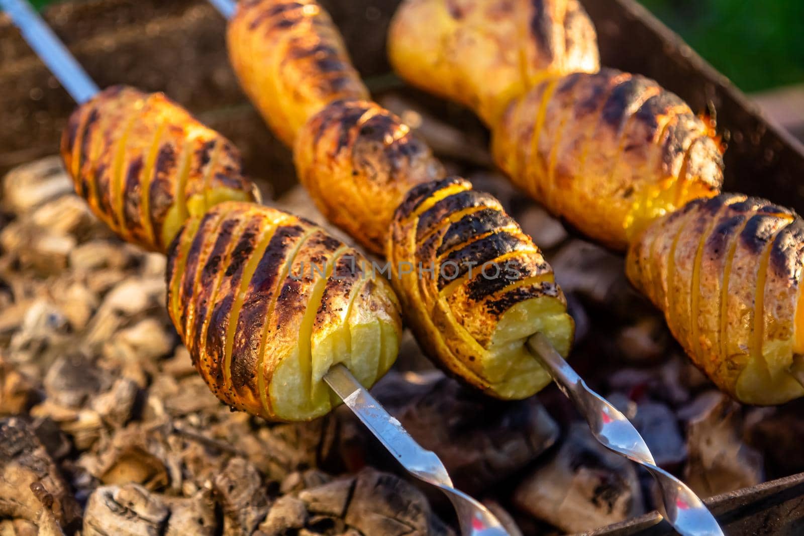 vegetarian skewers made from potatoes and mushrooms on the grill outdoors by Milanchikov