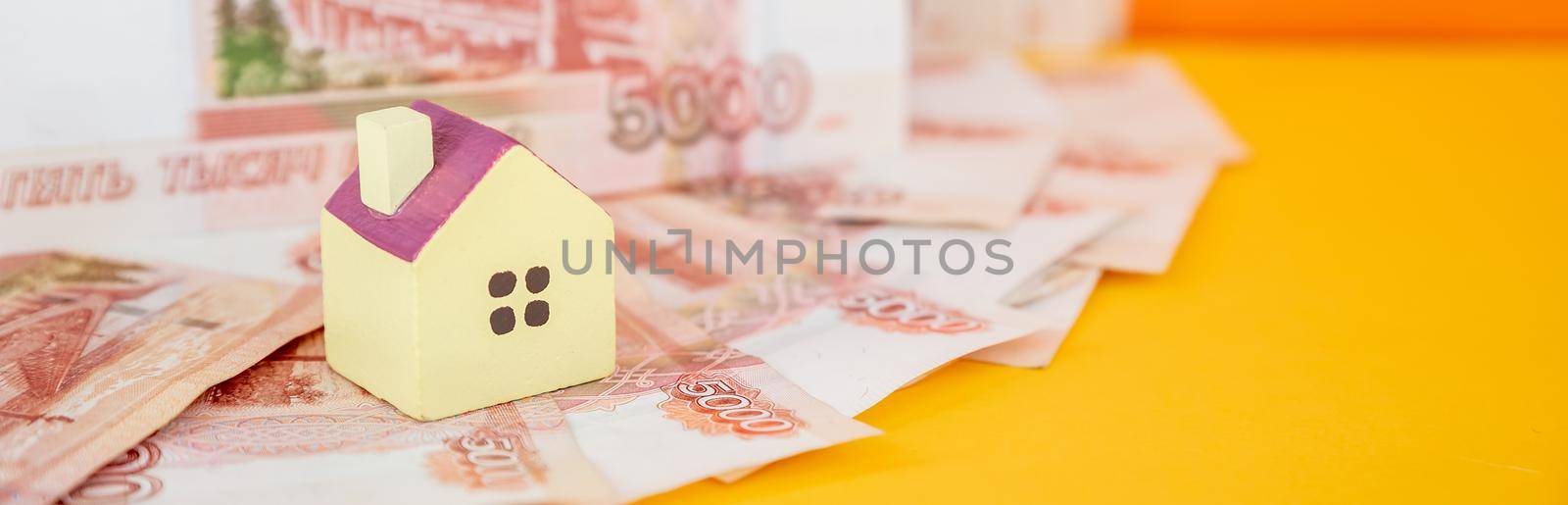 toy house on banknotes, buying your own home, mortgage, symbol of material well being