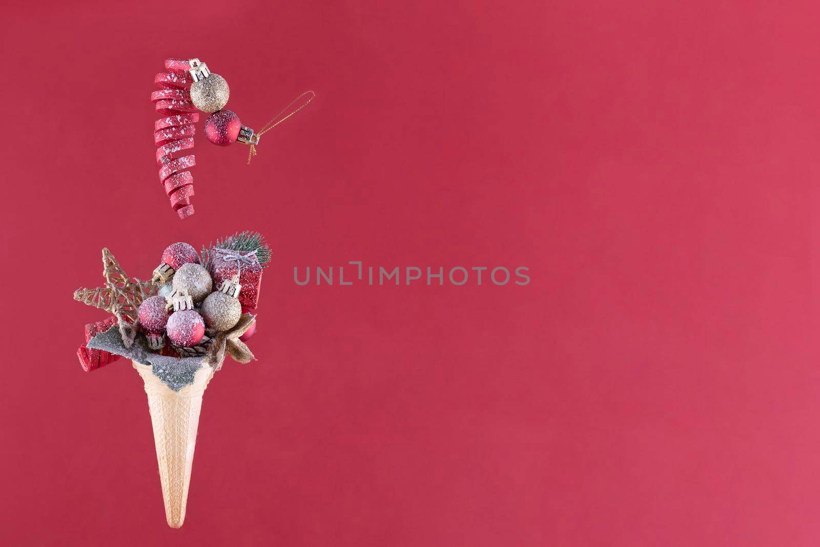 christmas decoration in ice cream cone on a red background behind the snow glass