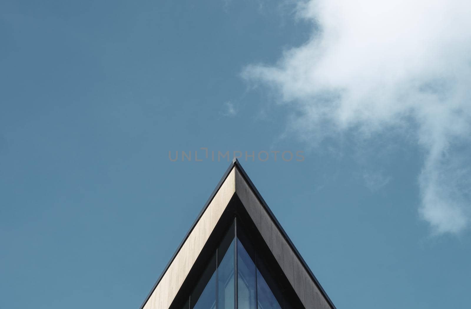 Abstract Architectural Image Of A Triangular Building Against A Blue Sky WIth Clouds And Copy Space