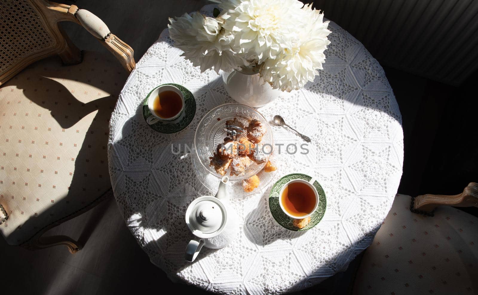 English style tea break, still life with flowers and donuts in the morning sun, homemade cakes, food from above. High quality photo