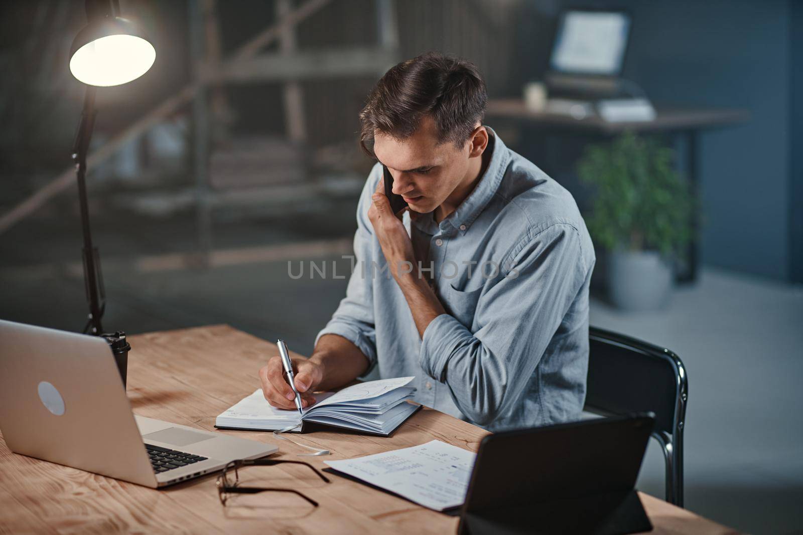 young businessman talking on a smartphone and using a laptop . close-up.