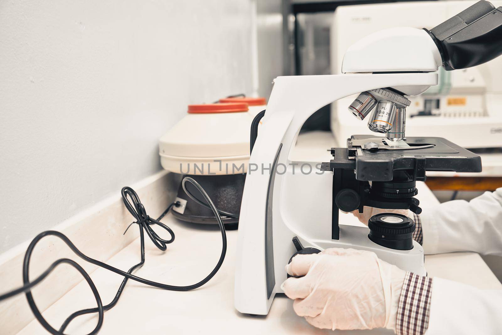 Unrecognizable Laboratorian Doing Blood Tests in a Microscope by cfalvarez
