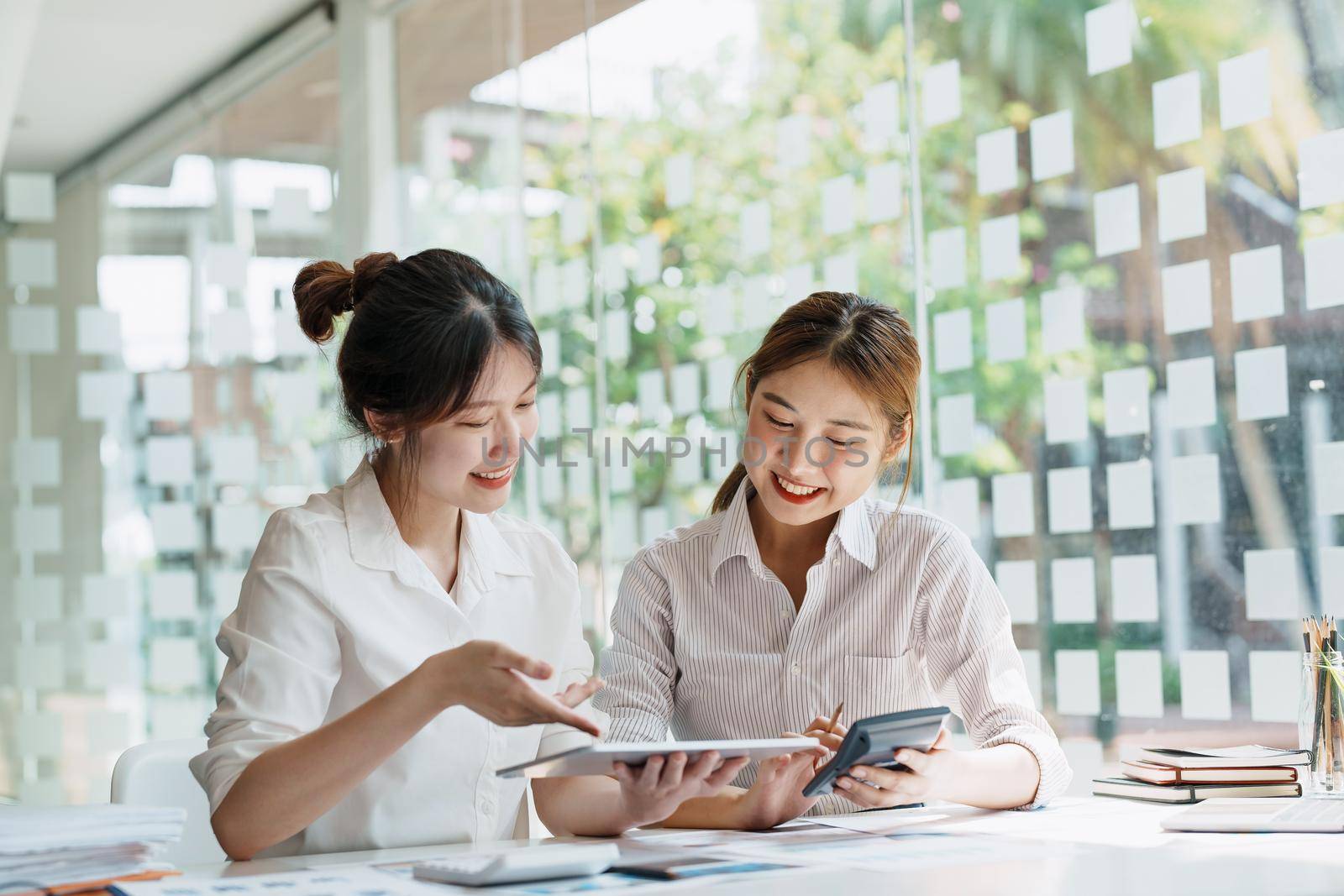 Negotiation, Analysis, Discussion, Portrait of an Asian women economist and marketer using tablet computer to plan investments and financial to prevent risks and losses for the company by Manastrong