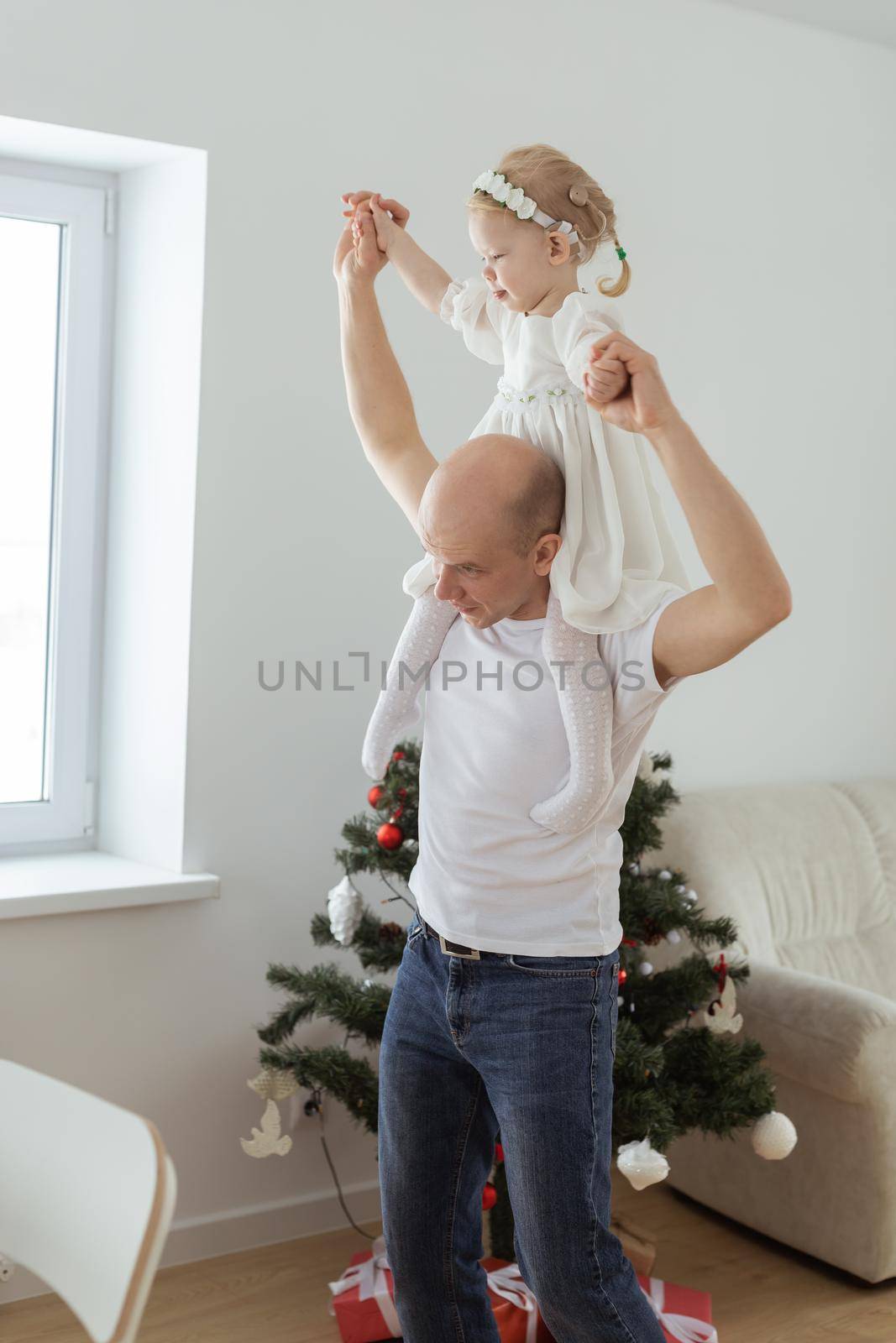Baby child with hearing aid and cochlear implant having fun with father on christmas tree background. Deaf , diversity and health concept by Satura86