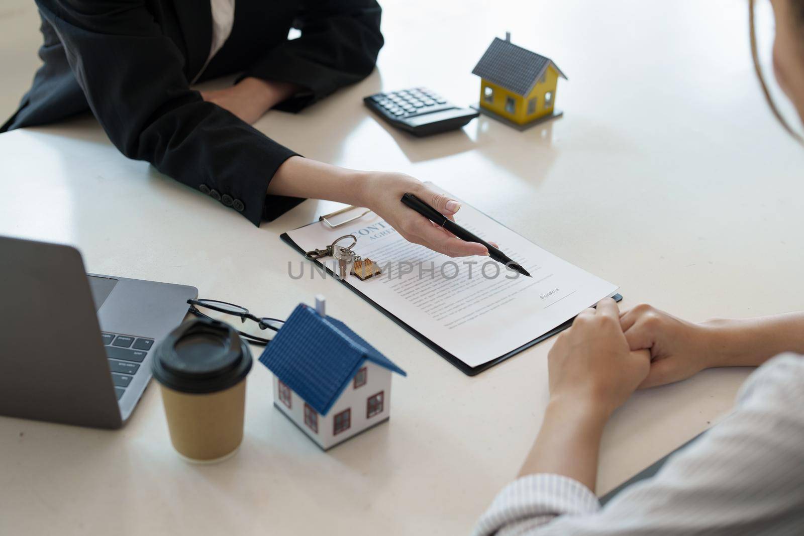 Guarantee, mortgage, agreement, contract, signed, real estate agent pointing to documents for customers to read the agreement before signing important documents by Manastrong