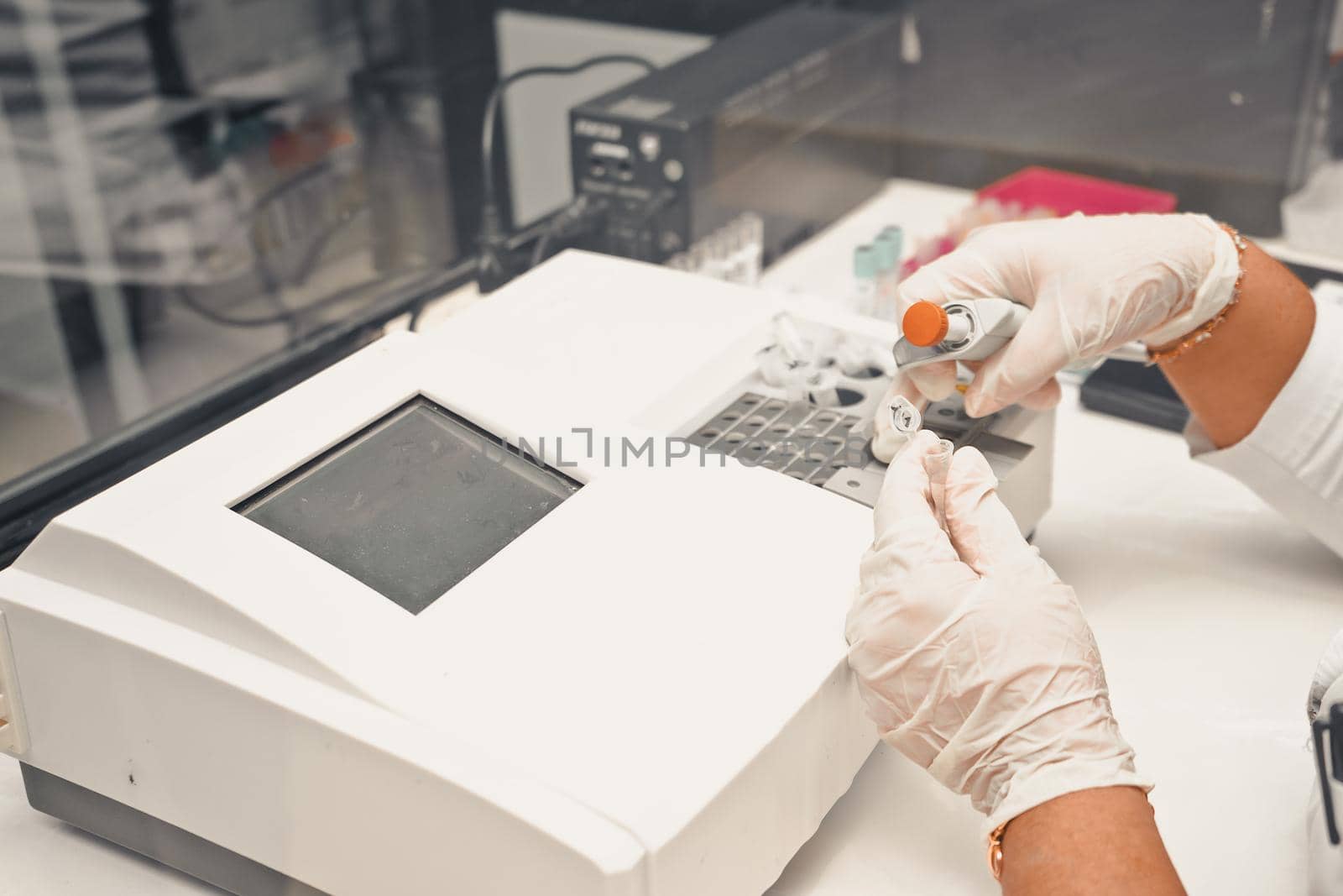 Unrecognizable Latin woman processing medical samples in laboratory equipment