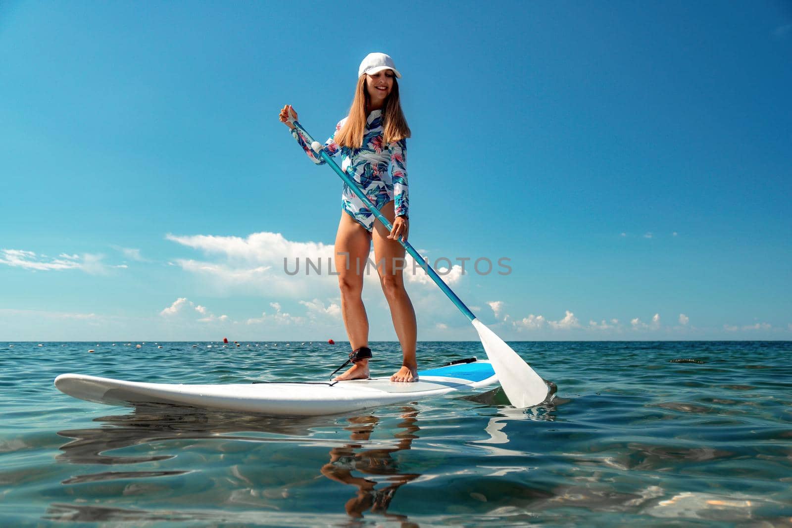 Healthy happy fit woman in bikini relaxing on a sup surfboard, floating on the clear turquoise sea water. Recreational Sports. Stand Up Paddle boarding. Summer fun, holidays travel. Active lifestyle by panophotograph