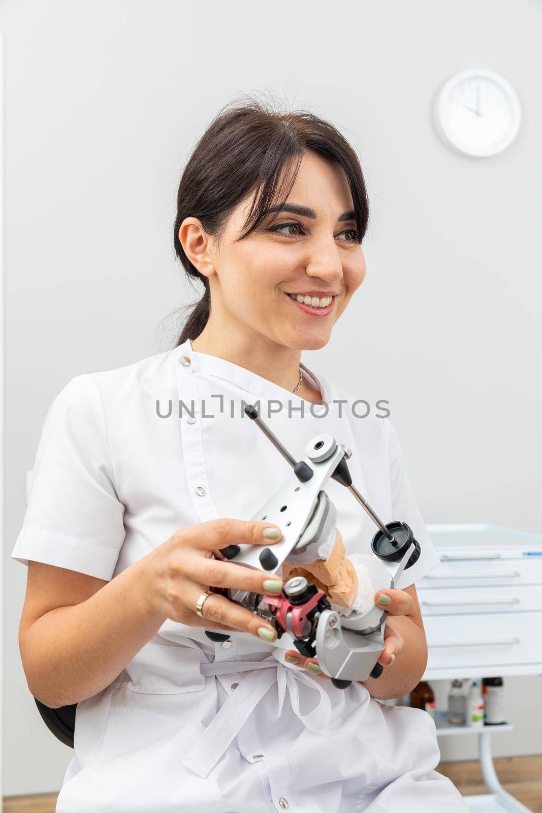 Dentist holding dental articulator with dental gypsum prosthesis model in dental laboratory by Mariakray