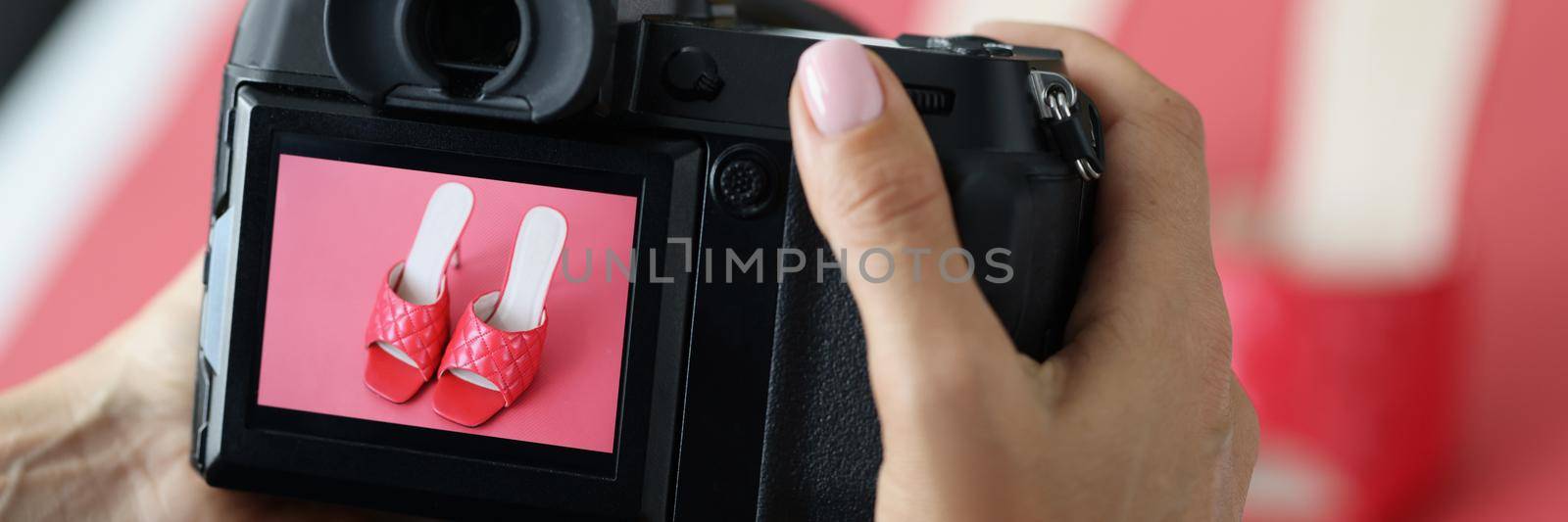 Close-up of woman professional photographer taking picture of red trendy shoes. Creating picture for advertisement. Fashion photographer, promotion concept