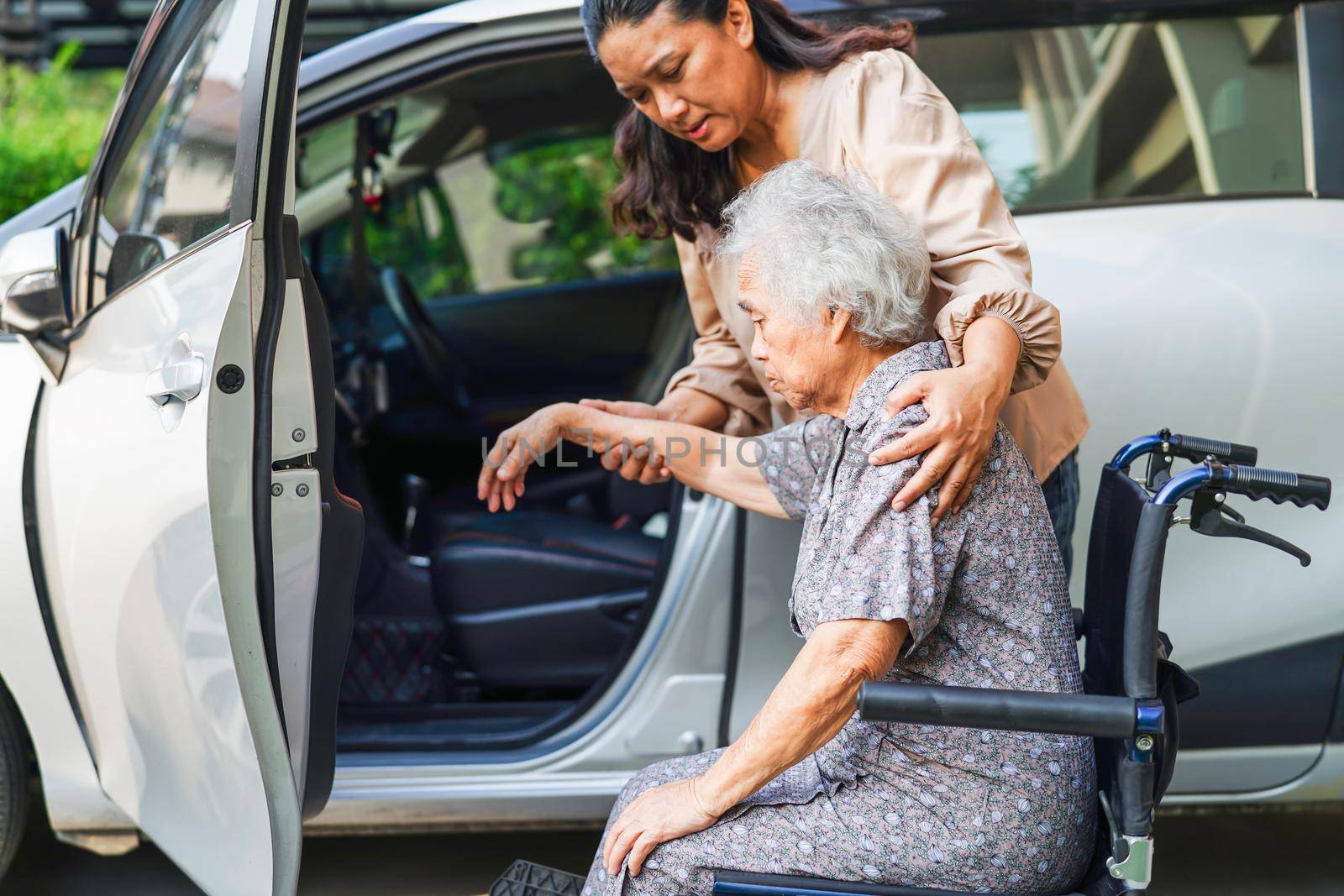 Caregiver help Asian elderly woman disability patient get in her car, medical concept. by sweettomato