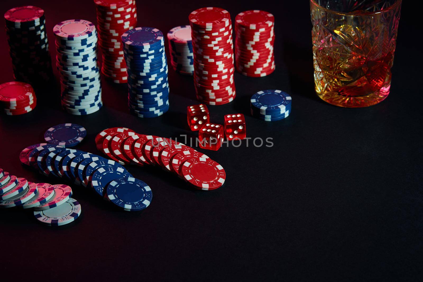 Poker chips and wine glass of cognac on dark table. Gambling by nazarovsergey