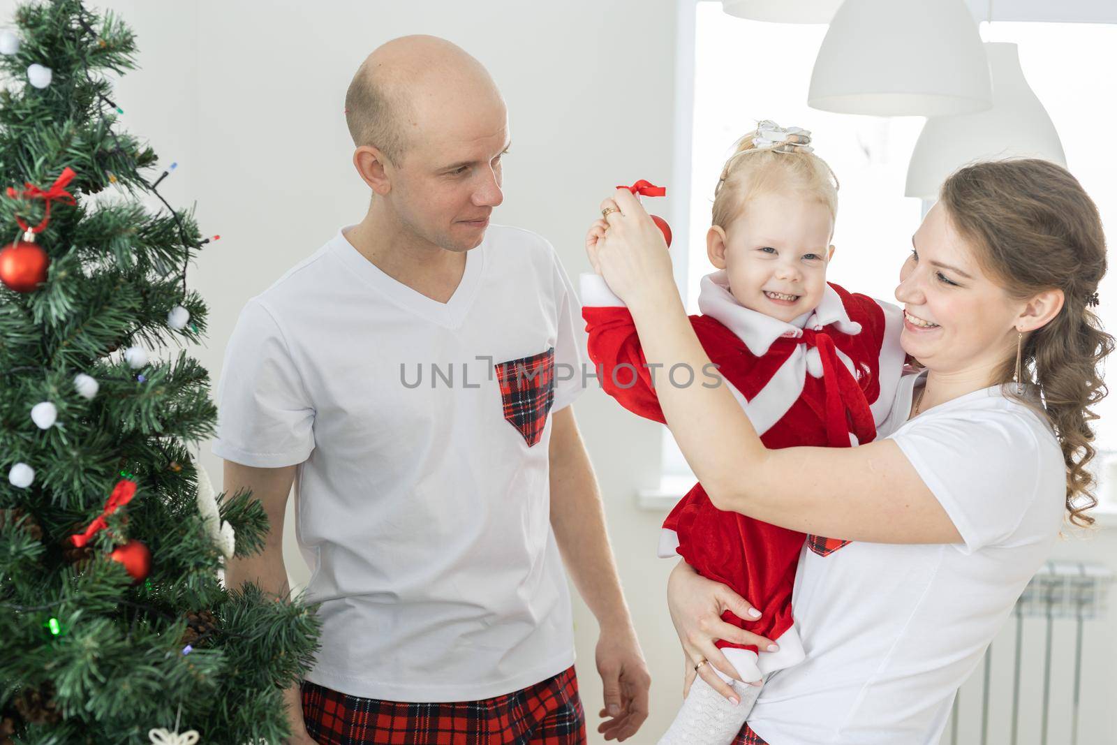 Father and mother with toddler daughter with cochlear implants having fun in christmas living room - inclusion and innovating treatment for deafness with cochlear implant surgery by Satura86