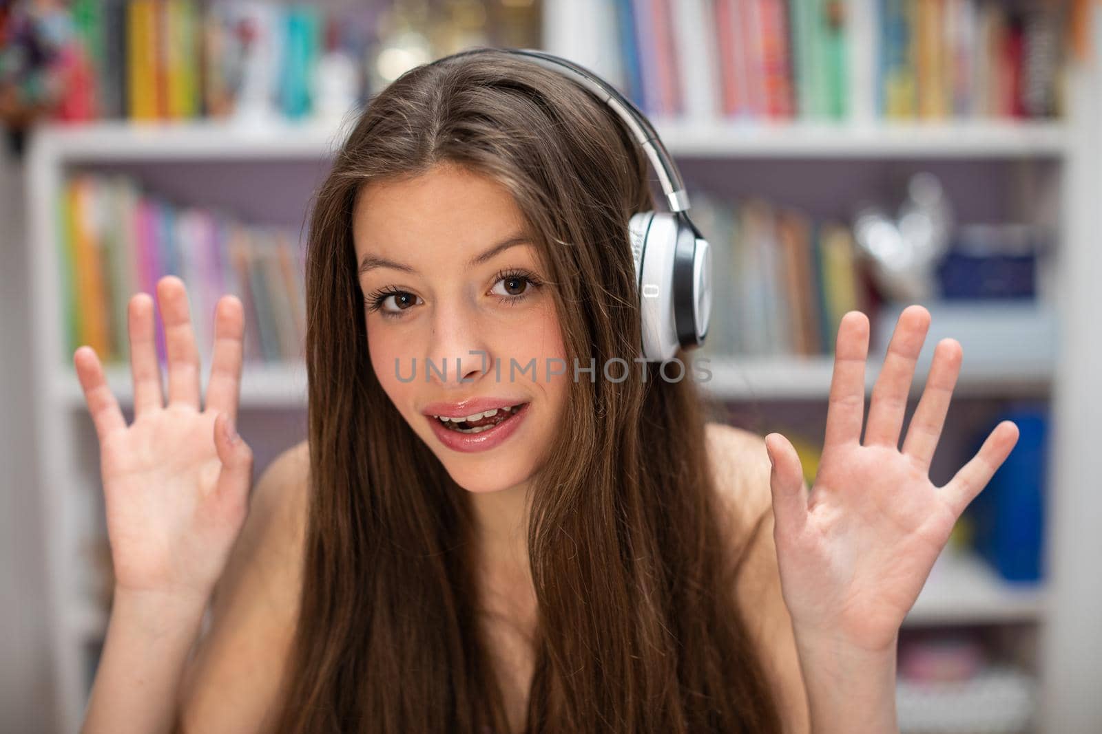A satisfied young girl. The inner part of the hand. Young brunette with long hair listens to music on wireless headphones.