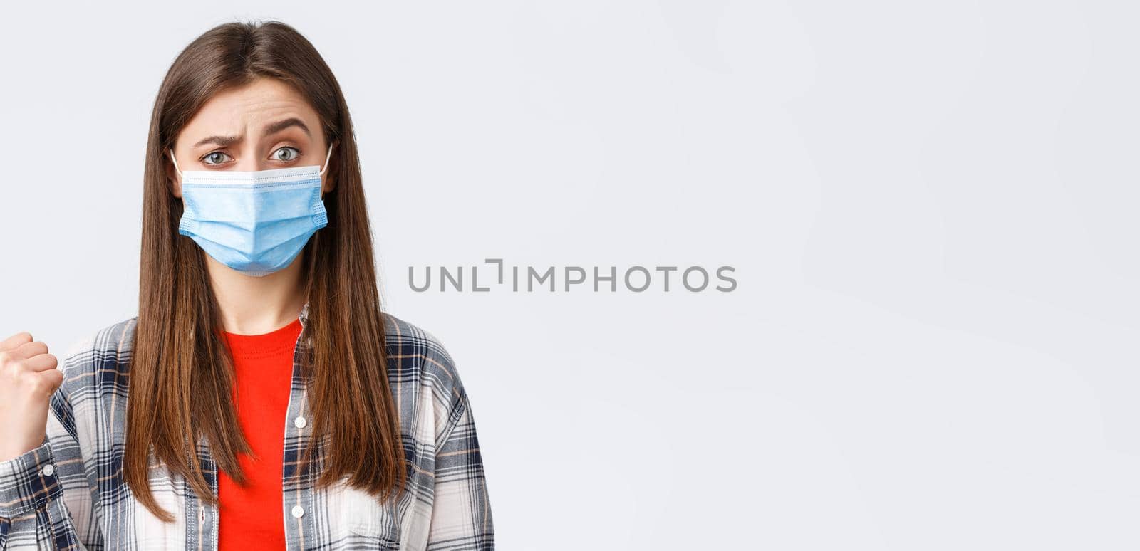 Coronavirus outbreak, leisure on quarantine, social distancing and emotions concept. Skeptical young woman in medical mask express disbelief towards banner to the left, pointing doubtful by Benzoix