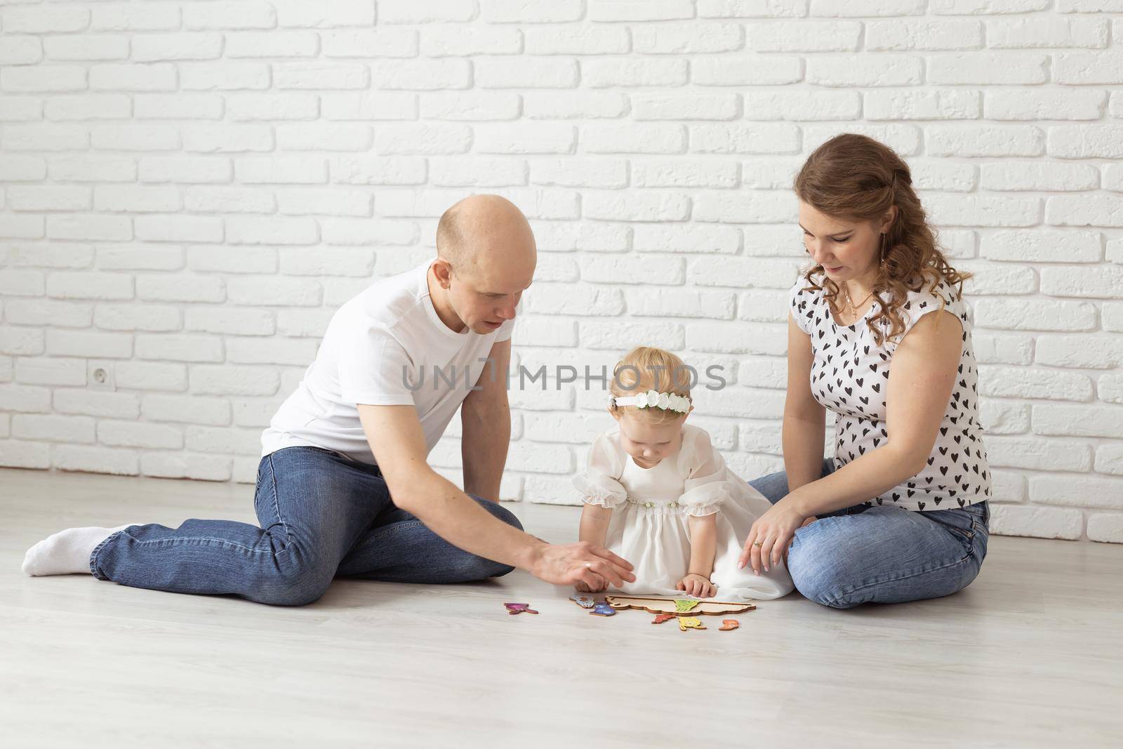 Baby child with hearing aids and cochlear implants plays with parents on floor. Deaf and rehabilitation and diversity concept by Satura86