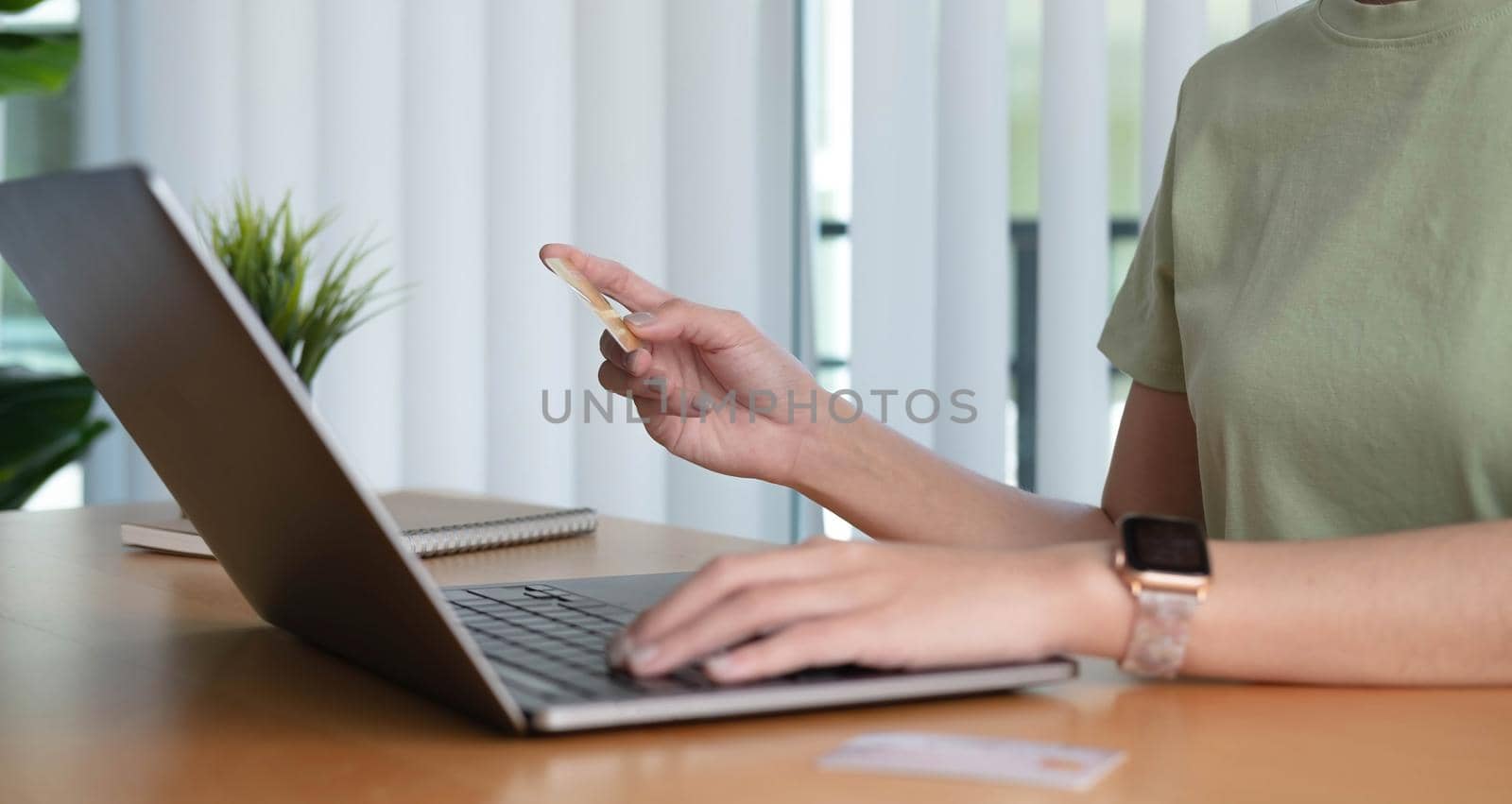 Online shopping. Young woman holding credit card and using laptop at home. African american girl working on computer at cafe. Business, e-commerce, internet banking, finance, freelance concept by wichayada