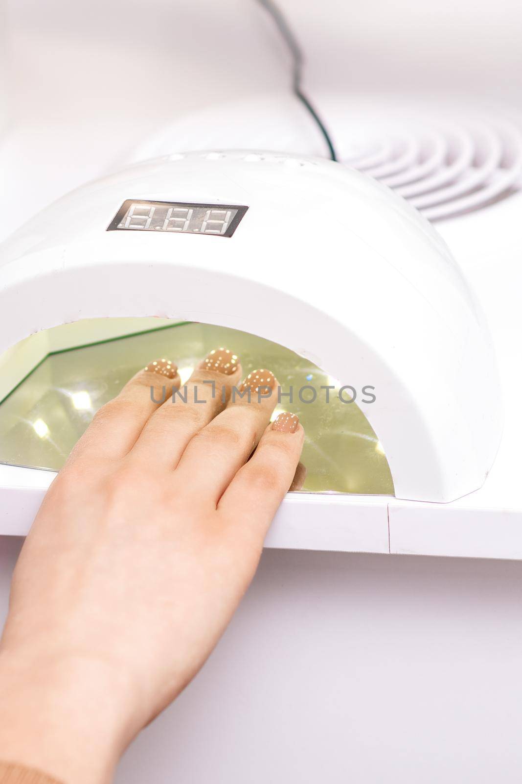 UV lamp gel polish manicure machine during process for drying of nails in beauty salon