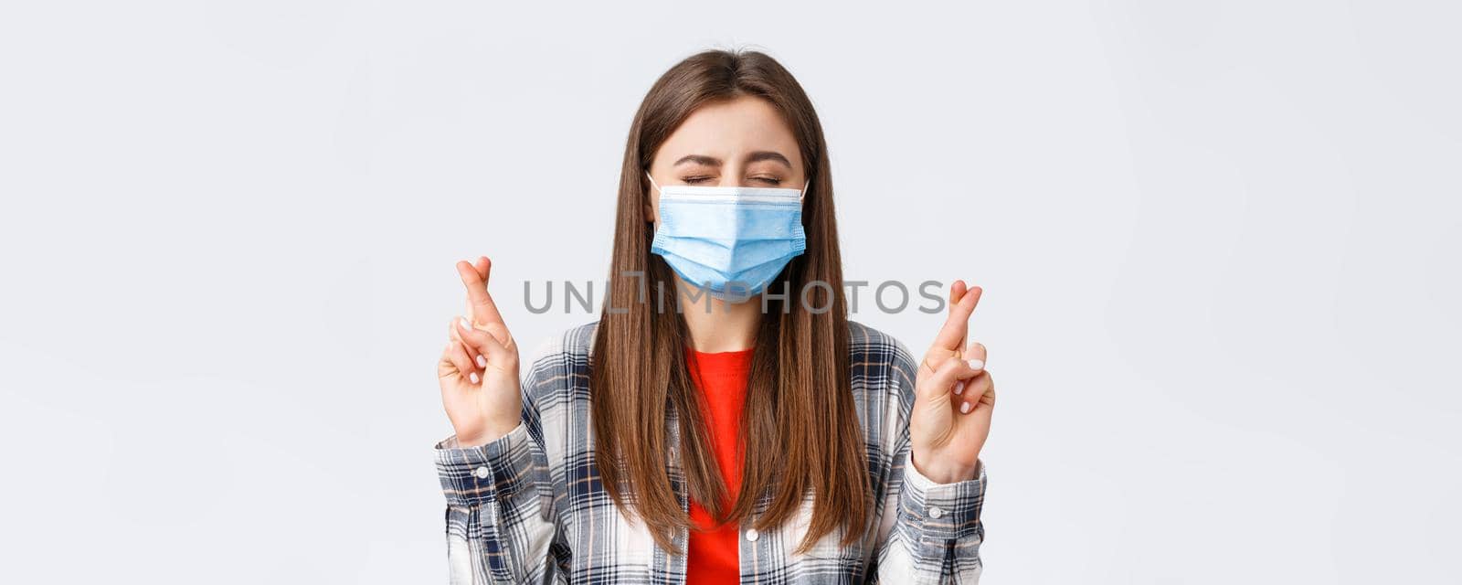 Coronavirus outbreak, leisure on quarantine, social distancing and emotions concept. Close-up of hopeful, dreamy young girl making wish, close eyes and cross fingers good luck.